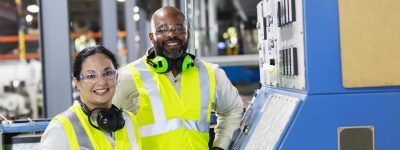 two manufacturing workers next to machine